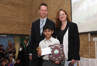 A Year 6 pupil receiving an award from Dr Toby Wilkinson and Dr Jocelyn Wyburd of Cambridge University